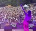 Sängerin steht auf einer Open-Air-Bühne vor großem Publikum, hebt die Hand zum Mitfeiern, begeisterte Konzertbesucher bei sommerlicher Festivalatmosphäre.